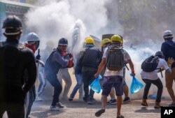 FILE - Anti-coup protesters use fire extinguishers to reduce the impact of teargas fired by riot policemen in Yangon, Myanmar, March 9, 2021.