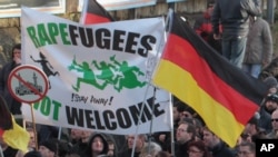 Demonstran sayap kanan memegang poster bertuliskan "Pengungsi pemerkosa tidak diterima! Pergi!" dan gambar masjid dicoret sambil melewati jalan-jalan di Cologne, Jerman, Sabtu, 9 Januari 2016. 