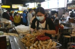 FILE - A vendor wears face mask to help curb the spread of the coronavirus and waits for customers at a night market in Taipei, April 8, 2020.