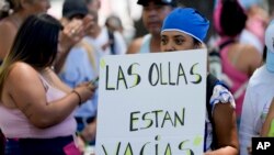 Seorang demonstran memegang poster yang bertuliskan "Panci kami kosong" dalam bahasa Spanyol saat berpartisipasi dalam aksi unjuk rasa di luar kediaman presiden Argentina di Buenos Aires, pada 23 Januari 2024. (Foto: AP/Natacha Pisarenko)