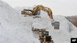 Heavy equipment being used to create a mountain of snow collected from surrounding parking lots at Shoppers World in Framingham, Massachusetts, January 28, 2011.
