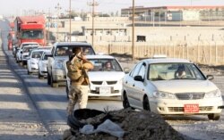 FILE - Kurdish peshmerga fighters stand at a checkpoint, north of Kirkuk, Iraq, Oct. 19, 2017.