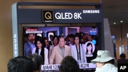 People watch a TV screen showing a file image of the late Samsung Electronics chairman Lee Kun-Hee, center, and his daughters during a news program at Seoul Railway Station in Seoul, South Korea, April 28, 2021. 