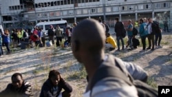 FILE - Migrants line up as they wait to be evacuated from a makeshift street camp, in Paris, France, July 7, 2017.