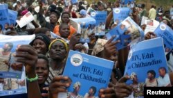 ARSIP – Orang tua, wali, teman, dan kerabat menyanyikan lagu-lagu tradisional dan mengusung poster pencegahan HIV/AIDS dalam upacara perayaan anak lelaki yang beranjak menjadi pria dewasa di desa Njoloma, Malawi, 27 Agustus 2006 (foto: REUTERS/Eldson Chagara (Malawi)