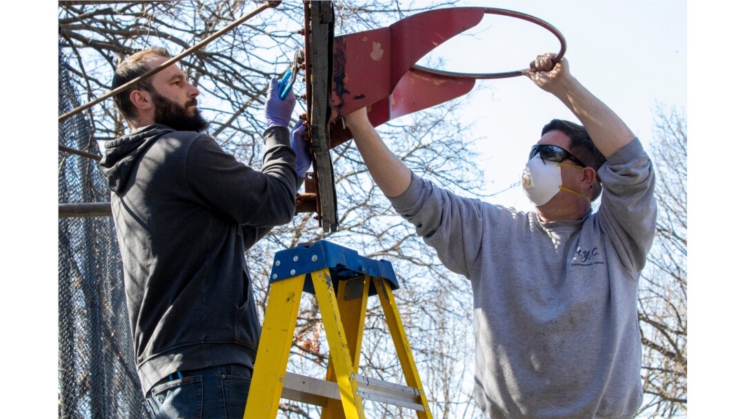 New York City Department of Parks and Recreation employees remove the basketball hoop from a court in Tompkins Square Park, March 26, 2020, in New York as part of the social distancing effort.