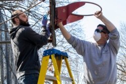 New York City Department of Parks and Recreation employees remove the basketball hoop from a court in Tompkins Square Park, March 26, 2020, in New York as part of the social distancing effort.