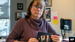 In this Feb. 11, 2019 photo, Carina Black sits in her office in Reno, Nev., holding an April 6, 1998 photo of herself with Nobel Peace Prize winner and former Costa Rican President Oscar Arias, center, and Richard Siegel, a former University of Nevada political science professor.
