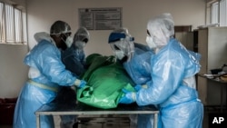 Members of a burial society prepare the body of a person who died from COVID-19, at the Avalon Cemetery in Lenasia, Johannesburg, South Africa, Dec. 26, 2020.