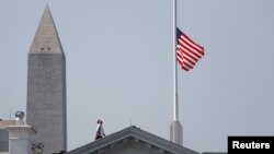 A worker looks up after lowering the flag over the White House in Washington to half-staff to honor victims of the shooting at the Capital Gazette Newspaper in Annapolis, Maryland, July 3, 2018.