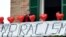 Une femme sur son balcon où elle a mis des ballons rouges portant le nom des victimes et une banderole disant "non au racisme" lors d'une manifestation antiraciste dans la ville de Macerata, en Italie, le 10 février 2018.