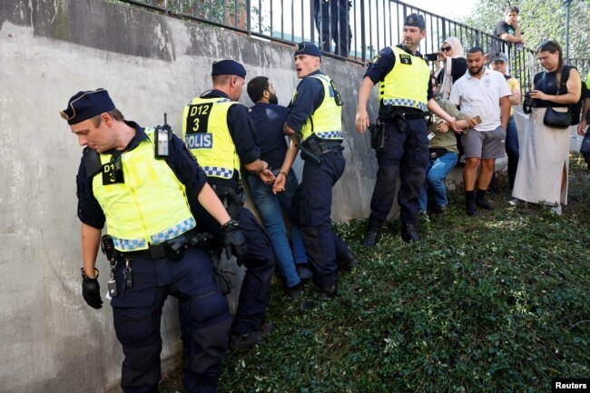 Polis Stockholm'deki camide Kuran-ı Kerim yakan göstericiye müdahale ederken, 28 Haziran 2023.