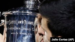 Novak Doković dari Serbia, mengangkat piala setelah mengalahkan Juan Martin del Potro dari Argentina dalam laga final tunggal putra turnamen AS Terbuka di New York, 9 September 2018.