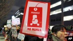 Des manifestants brandissent des pancartes lors d'un rassemblement anti-nucléaire près du bureau du Premier ministre à Tokyo, le 11 mars 2016.