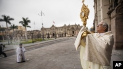 ARCHIVO - El Arzobispo de Lima Carlos Castillo sostiene la hostia consagrada durante la Misa de Corpus Christi frente a la Catedral de Lima, Perú, el 14 de junio de 2020. 