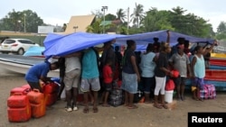 Voters and their families shelter from the rain while waiting to board small boats to vote in their provinces, in the capital Honiara, Solomon Islands, April 16, 2024.