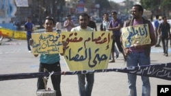 Demonstrators hold banners as they protest in the Martyrs Square in Suez, Egypt, as hundreds of Egyptians attacked a courtroom in Cairo, July 5, 2011