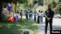 FILE - A man stands next to the memorial for Ahmaud Arbery at the place where he was shot and killed in February, in Brunswick, Georgia, May 8, 2020.