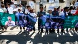 Protesters hold banner printed with detained activist Vorn Pao in front of the Appeals Court during a rally in Phnom Penh, Cambodia, Monday, March 24, 2014. The protesters demanded the release of the 21 anti-government demonstrators, including Vorn Pao, who were arrested during a crackdown on a labor protesting in January. (AP Photo/Heng Sinith)