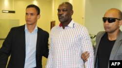 Top level Rwandan genocide suspect Ladislas Ntaganzwa, center, is escorted by security upon his arrival at the airport of Kigali, March 20, 2016.