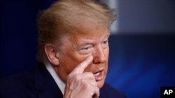 President Donald Trump gestures as he talks about the first coronavirus test he had, during a coronavirus task force briefing at the White House, April 18, 2020, in Washington.