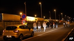 Un automóvil de seguridad de la sociedad del Eurotunnel sigue a un grupo de migrantes, en Calais, norte de Francia, el miércoles, 29 de julio, de 2015.