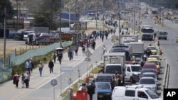 Los pasajeros caminan por una avenida bloqueada por camioneros que protestan por el aumento anunciado por el gobierno en los precios del diésel en Bogotá, Colombia, el martes 3 de septiembre de 2024.