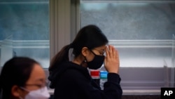 FILE - A student wearing a face mask prays before the start of the annual college entrance examination amid the coronavirus pandemic in Seoul, South Korea, Dec. 3, 2020.