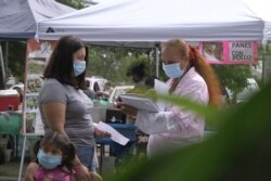 FILE - A "promotora" (health promoter) from CASA, a Hispanic advocacy group, tries to enroll Latinos as volunteers to test a potential COVID-19 vaccine, at a farmers market in Takoma Park, Maryland, Sept. 9, 2020.