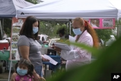 FILE - A "promotora" (health promoter) from CASA, a Hispanic advocacy group, tries to enroll Latinos as volunteers to test a potential COVID-19 vaccine, at a farmers market in Takoma Park, Maryland, Sept. 9, 2020.