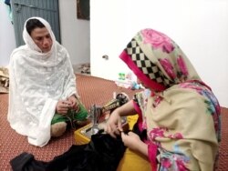 Rani Khan looks at one of her students during a tailoring lesson in Islamabad, March 22, 2021.