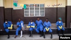 FILE - Health workers rest outside a quarantine zone at a Red Cross facility in the town of Koidu, Kono district in eastern Sierra Leone, Dec. 19, 2014. 