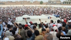 FILE - People gather around an ambulance carrying the coffin of Awami National Party (ANP) candidate Haroon Bilour, who was among those killed in a suicide attack during a July 10 election campaign meeting, in Peshawar, Pakistan, July 11, 2018.