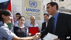 A Palestinian school girl, left, hands a letter, addressed to the United Nations Secretary-General Ban Ki-moon, to UN officer Pascale Soto, right, during a rally to support the Palestinian statehood bid in the United Nations, in the West Bank city of Rama