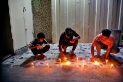 People light candles at the site of a bombing in Wahailat market in Sadr City, Iraq, July. 19, 2021.
