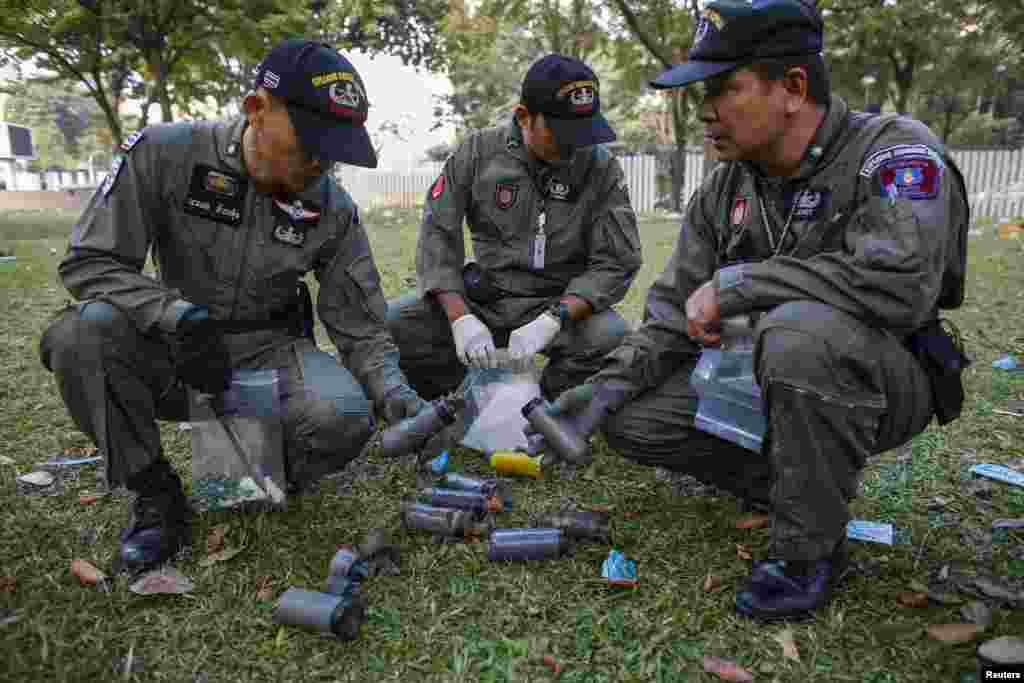 Thai security personnel inspect unidentified objects at the Thai-Japan youth stadium, the site of fierce clashes between anti-government protesters and riot police, in central Bangkok, Thailand, Dec. 27, 2013. 