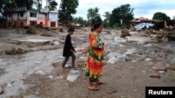 Residents are seen near a mosque in a village devastated by flash floods in Salvador, Lanao del Norte in southern Philippines, Dec. 24, 2017.