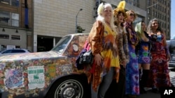 Women stand next to a psychedelic Rolls Royce at the California Historical Society in San Francisco.The car belongs to Donna Huggins (second from left) and is covered with original music posters and artwork from 1967. (AP Photo/Eric Risberg)