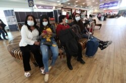 People wearing face masks wearing masks wait for the arrival of their relatives at the Mariscal Sucre International Airport, in Quito, Ecuador, Feb. 29, 2020.