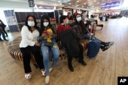 People wearing face masks wearing masks wait for the arrival of their relatives at the Mariscal Sucre International Airport, in Quito, Ecuador, Feb. 29, 2020.