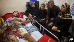 Palestinian surfer Raed Jadallah, left, lies on a bed as his father, mother and brothers, visit him at the Shifa hospital in Gaza, April 9, 2018. Jadallah is among the nearly 1,300 people that Palestinian health officials said have been shot and wounded by Israeli soldiers during mass border protests over the past two weeks.