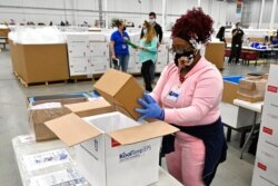 An employee with the McKesson Corporation packs a box of the Johnson and Johnson COVID-19 vaccine into a cooler for shipping from the facility in Shepherdsville, Ky., March 1, 2021.