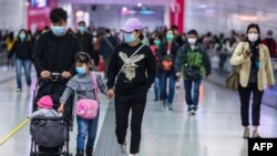 People wearing facemasks walk through a train station on the second day of the Lunar New Year of the Rat in Hong Kong on January 26, 2020, as a preventative measure following a coronavirus outbreak which began in the Chinese city of Wuhan.