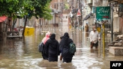 People wade through floodwaters after heavy monsoon rains in Multan, Pakistan, Aug. 30, 2024. 