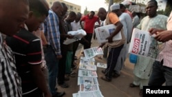 FILE - People gather to browse through newspapers at a newsstand in Abuja, Nigeria, Jan. 26, 2015. 