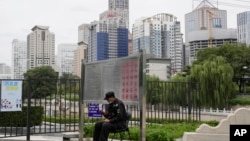 FILE - A security guard mans his post across from the central business district in Beijing, China, Tuesday, Oct. 5, 2021.