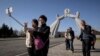 FILE - Tourists from China pose for photos before the Three Charters monument in Pyongyang, April 15, 2019. North Korea will ban foreign tourists to protect itself against a new virus, a major tour operator said Jan. 22, 2020.