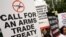 FILE - Activists campaigning for a global arms trade treaty hold placards during a protest in New Delhi, India.