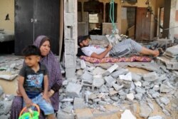 Palestinians rest amid debris after returning home following an Israel-Hamas truce, in Beit Hanoun in the northern Gaza Strip, May 21, 2021.