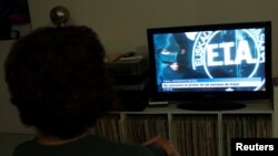 A woman watches a news program announcing the dissolution of armed Basque separatists ETA set for the first week of May, in Guernica, April 18, 2018.